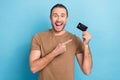 Photo of entrepreneur man wear t-shirt direct finger surprised demonstrate plastic credit card wireless nfc payment