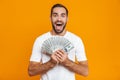 Photo of european man 30s in casual wear holding bunch of money, isolated over yellow background Royalty Free Stock Photo