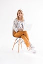 Photo of european nice woman wearing casual clothes smiling at camera and using laptop while sitting in chair Royalty Free Stock Photo