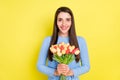 Photo of excited adorable young woman dressed blue clothes holding bouquet smiling isolated yellow color background Royalty Free Stock Photo