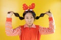 Portrait of cheerful happy asian girl wearing christmas deer costume standing isolated on yellow background, copy space. Royalty Free Stock Photo