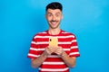 Photo of excited cheerful young man hold smartphone comment share media isolated on blue color background