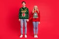 Photo of excited dreamy curious couple hold hands empty space wear ugly sweater jeans shoes isolated red color