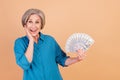 Photo of excited ecstatic woman with bob hairdo dressed blue shirt hold bunch of money palm on cheek isolated on pastel Royalty Free Stock Photo