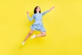 Photo of excited funky young woman dressed blue clothes jumping high looking empty space smiling isolated yellow color Royalty Free Stock Photo
