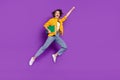 Photo of excited funny young woman dressed yellow shirt jumping high holding copybooks rising fist  purple color Royalty Free Stock Photo