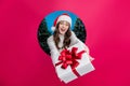 Photo of excited girl dressed santa claus helper x-mas hat giving you gift breakthrough paper hole empty space isolated Royalty Free Stock Photo