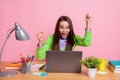 Photo excited girl sit table laptop win raise fists scream wear green shirt isolated pastel color background