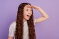 Photo of excited happy little girl look forward empty space isolated on purple background