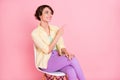 Photo of excited pretty young woman wear yellow shirt sitting chair pointing empty space isolated pink color background Royalty Free Stock Photo
