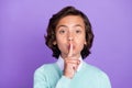 Photo of excited serious schoolboy wear teal pullover finger lips asking keep secret isolated purple color background