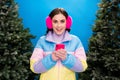 Photo of excited sweet girl dressed windbreaker typing instagram twitter facebook gadget outdoors isolated blue color Royalty Free Stock Photo