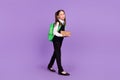 Photo of exhausted pupil girl carry pile boring book walk wear bag glasses uniform isolated purple color background