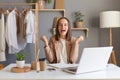 Photo of extremely happy Caucasian brown-haired woman designer wearing beige jacket, posing with clenched fists, celebrating Royalty Free Stock Photo