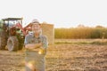 Photo of farm tractor, round bale hay in field with yellow lens flare in background Royalty Free Stock Photo