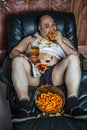 Overweight man eating and watching TV Royalty Free Stock Photo