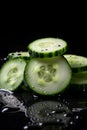 Ring-sliced cucumbers with water droplets on the table in close-up.