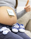 Photo of female abdomen with little blue male shoes and written word boy on the paper. Royalty Free Stock Photo