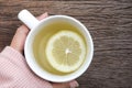 Photo of female hands in pink sweater touching white cup of tea with lemon slice on wooden table. Royalty Free Stock Photo