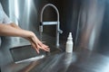 Close-up photo of a woman hands in the process of washing with water under a tap