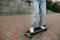 Photo of female legs riding on a longboard down the street. A woman skates around the city. Skateboarding concept Royalty Free Stock Photo