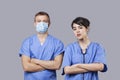 Portrait of female and male surgeons standing with arms crossed over gray background