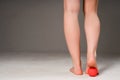 Photo of female sports legs. A woman does a foot massage with a red massage ball. Isolated on gray background Royalty Free Stock Photo