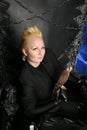 Photo of a female witch queen holding bird and sitting on a gothic scary black throne