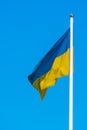 Photo of a flag of Ukraine are sways in the wind on flagpole against a background of clear blue sky Royalty Free Stock Photo