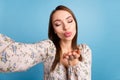 Photo of flirty brown hairdo millennial lady do selfie blow kiss wear floral blouse isolated on blue color background