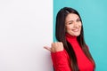 Photo of flirty pretty mature woman wear red sweater winking pointing thumb white wall empty space smiling isolated