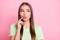 Photo of flirty tricky young lady wear green t-shirt finger pouted lips looking empty space isolated pastel pink color