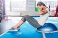 Focused sporty beautiful young athletic brunette woman in gray leggings and white t-shirt working in gym doing exercises for Royalty Free Stock Photo