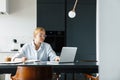 Photo of focused woman making down notes while working with laptop