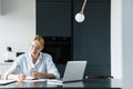 Photo of focused young woman working with cellphone and laptop