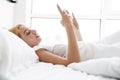 Photo of focused young woman using cellphone while lying in bed