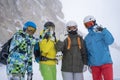 Photo of four happy snowboarders in helmet on background of mountains.