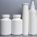 Photo of four plastic cans for package pills and vitamins and antiseptic spray for protection against coronavirus KOVID-19 on a gr