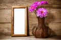 Photo frame,beautiful pink flower in vase on wood background.