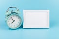 Photo frame and blue alarm clock on blue background with copy space Royalty Free Stock Photo