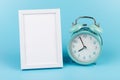 Photo frame and blue alarm clock on blue background with copy space Royalty Free Stock Photo