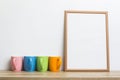 A photo frame with colorful cups on a wooden table. Royalty Free Stock Photo