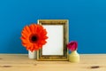 Photo frame with flower decoration on wooden table with blue background Royalty Free Stock Photo