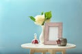 Photo frame with flowers in vase and candle holder on white table against color background Royalty Free Stock Photo