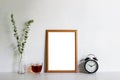 A photo frame and green leaves, clock and coffee cup on table