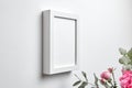 Photo frame mockup hanging on white concrete wall and bouquet of pink roses with eucalyptus leaves. Blank picture frame, interior Royalty Free Stock Photo