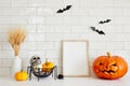 Photo frame mockup with Jack o lantern, pumpkins, skull, vase of dried flowers on table in Scandinavian style interior kitchen