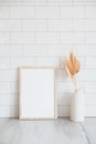 Photo frame mockup and vase of dried flowers on table. Brick tiles wall on background. Scandinavian home decor, nordic style Royalty Free Stock Photo