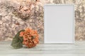 Photo frame with orange flower on wooden table and natural bright tree background. Place your text or photo. Concept card. Royalty Free Stock Photo