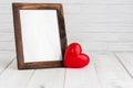 Photo frame and red heart on white wood table with copy sapce, love concept